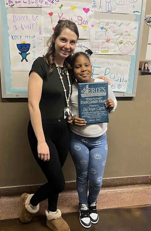 Da'kiya Clark, Edison's Stairclimber recipient for January, poses with a school staff member and her plaque.